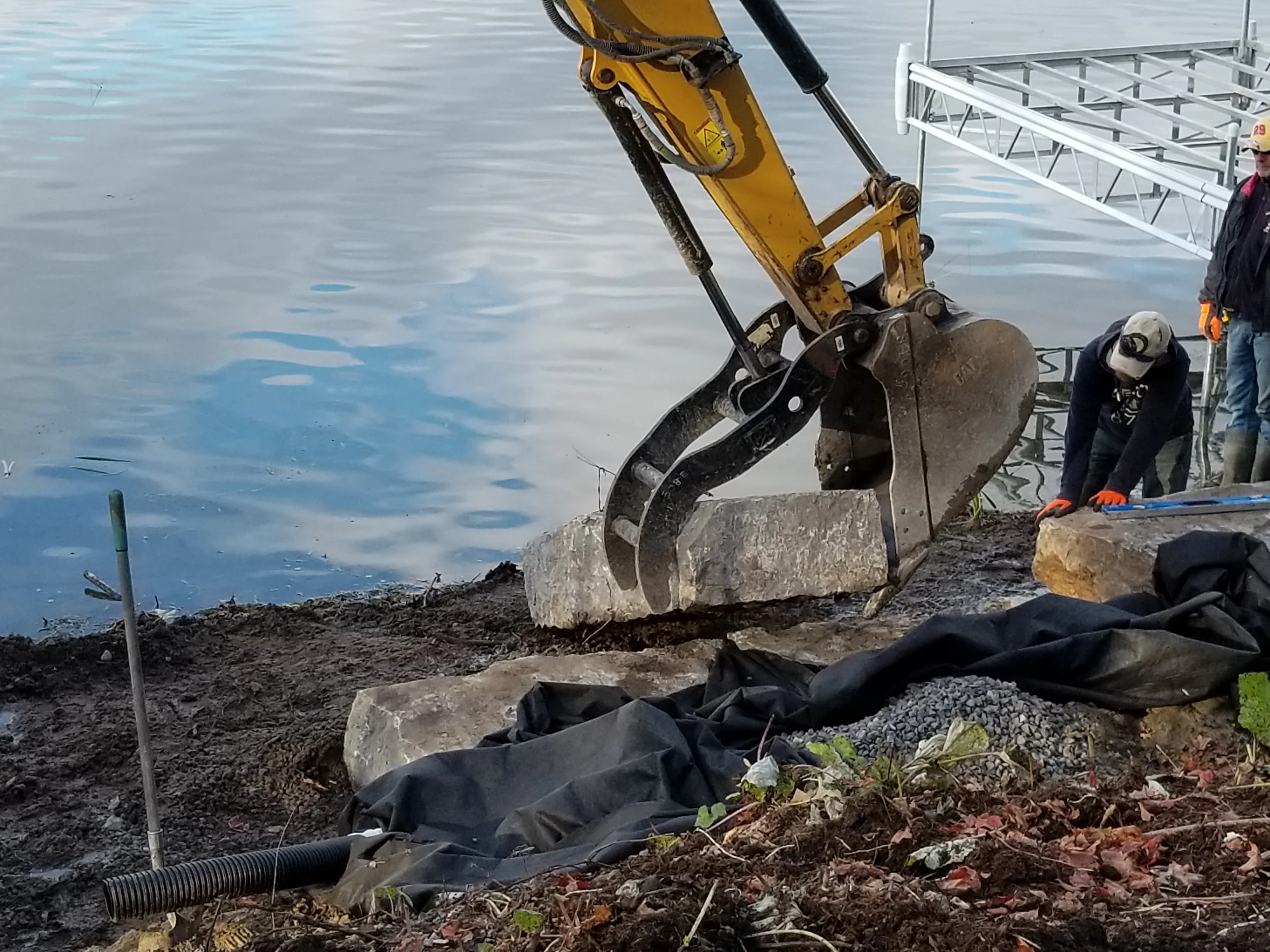 Excavator placing stone along a shoreline