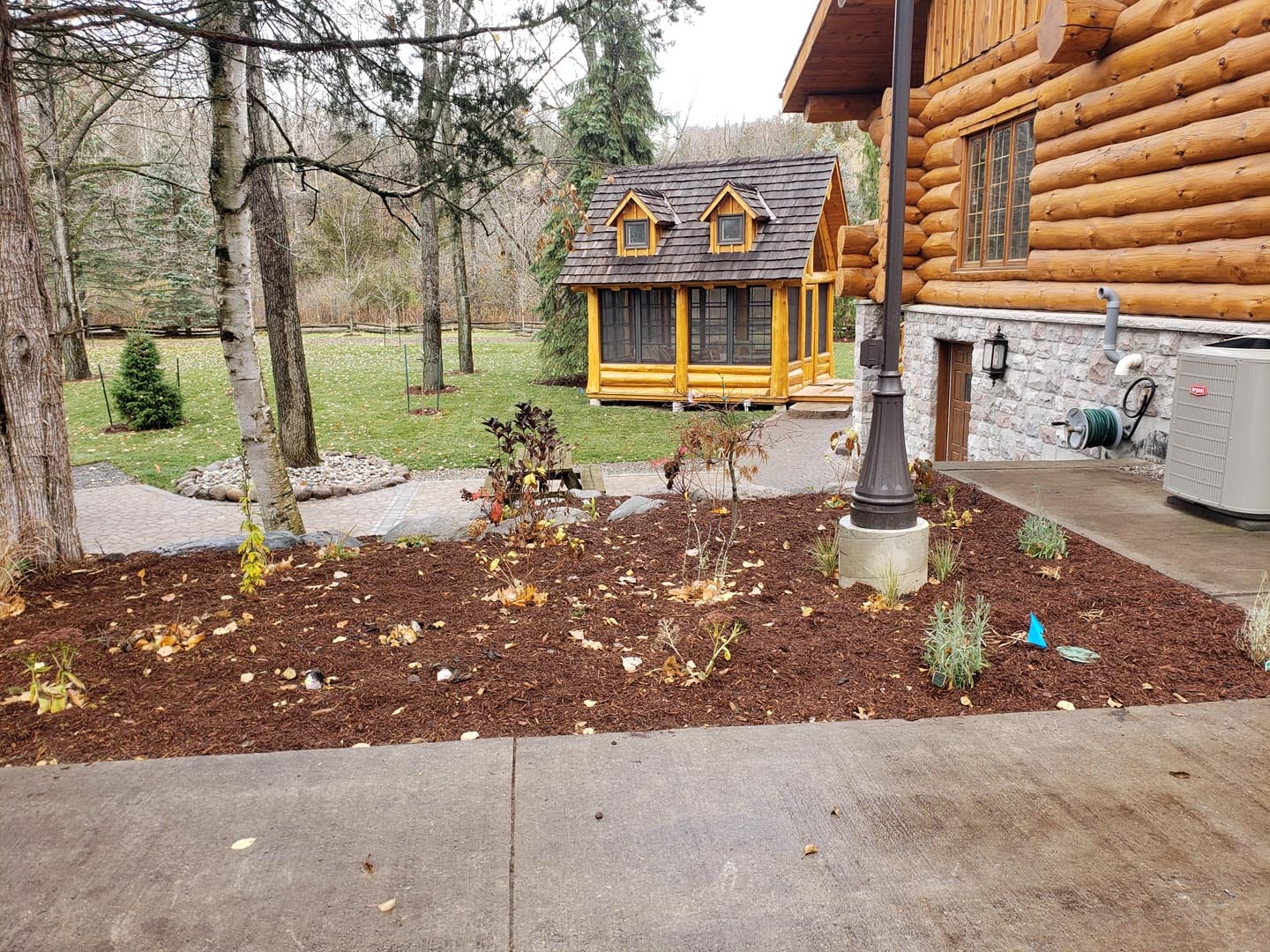 Freshly mulched garden bed beside a log home