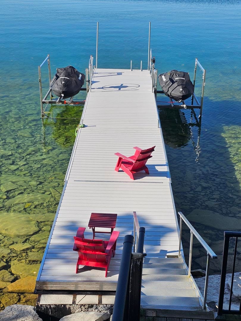 Floating dock with red Muskoka chairs on the water