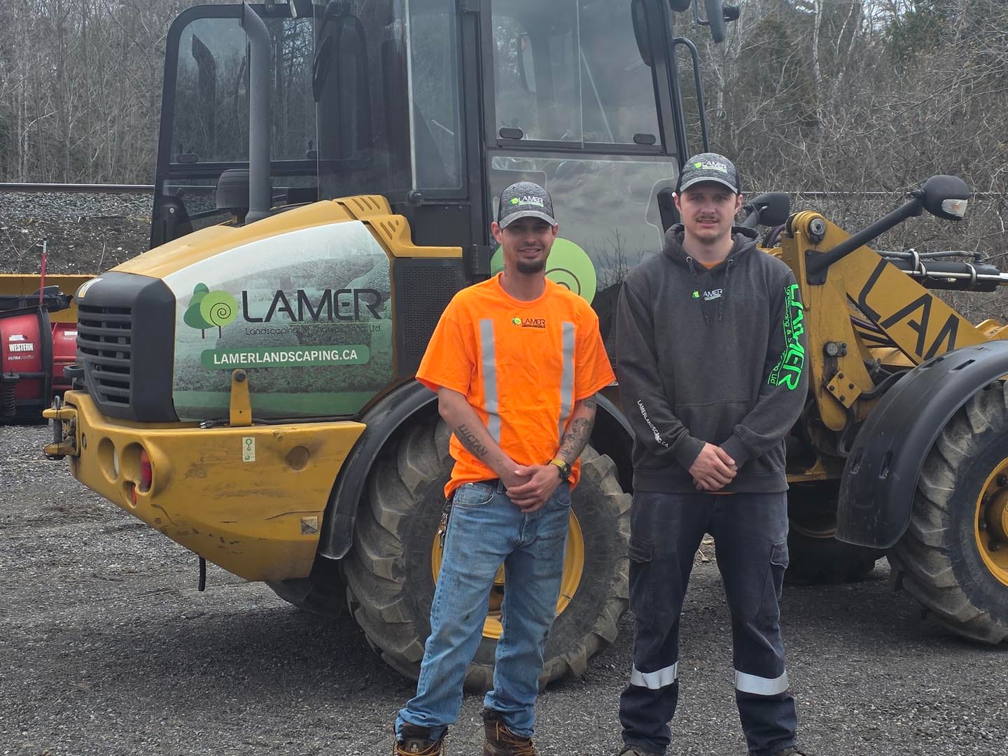 Two Lamer crew members in front of a company wheel loader