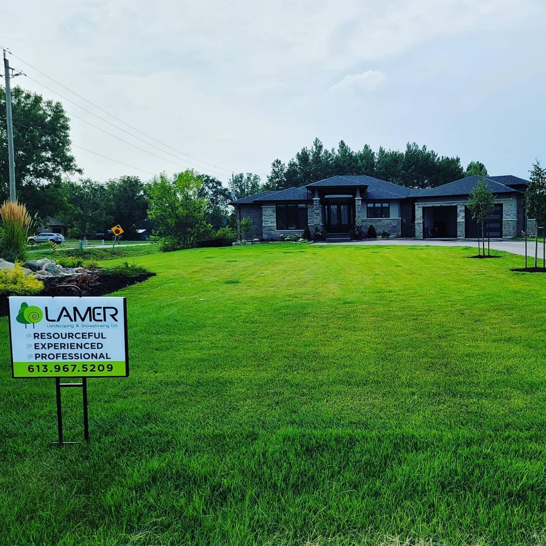 Freshly mowed front lawn with a Lamer Landscaping sign
