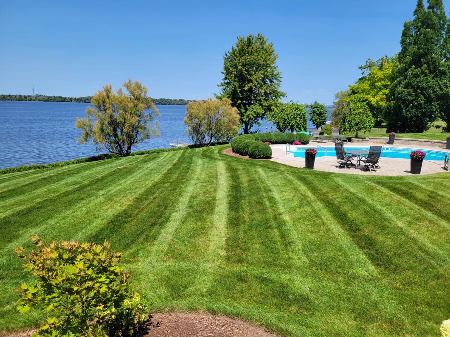 Freshly cut striped lawn on a waterfront property with an in-ground pool