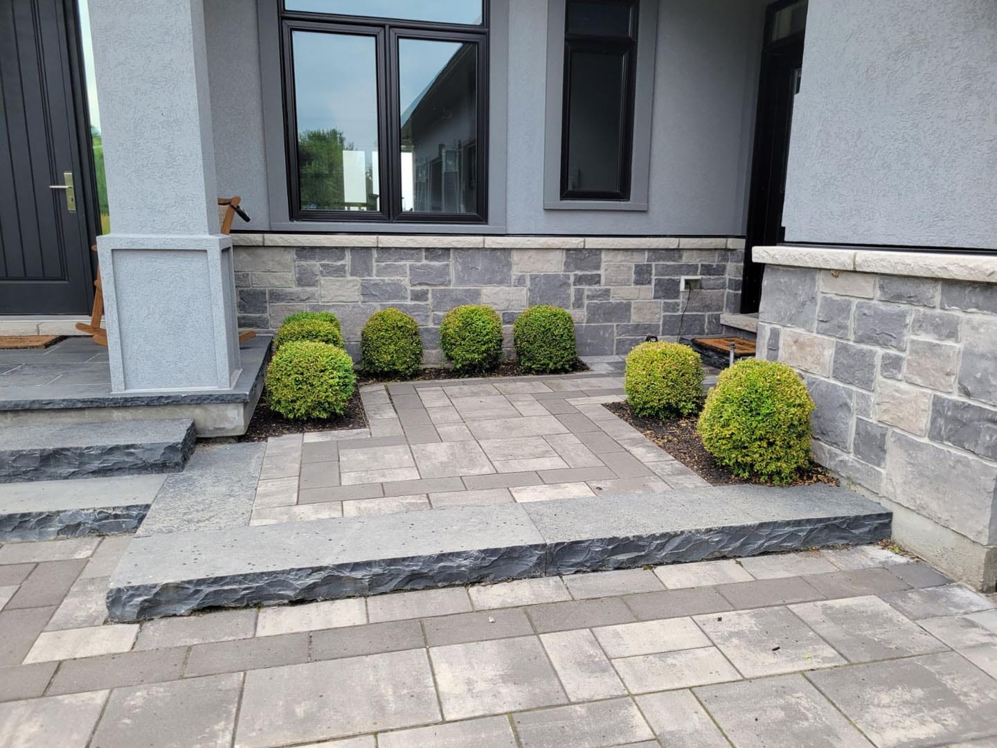 Front entrance with interlock steps and a freshly mulched bed of shrubs