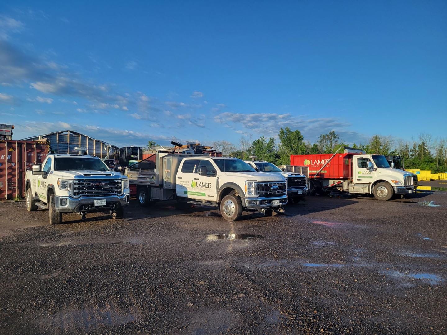 Lamer Landscaping trucks and equipment lined up at the yard at sunrise