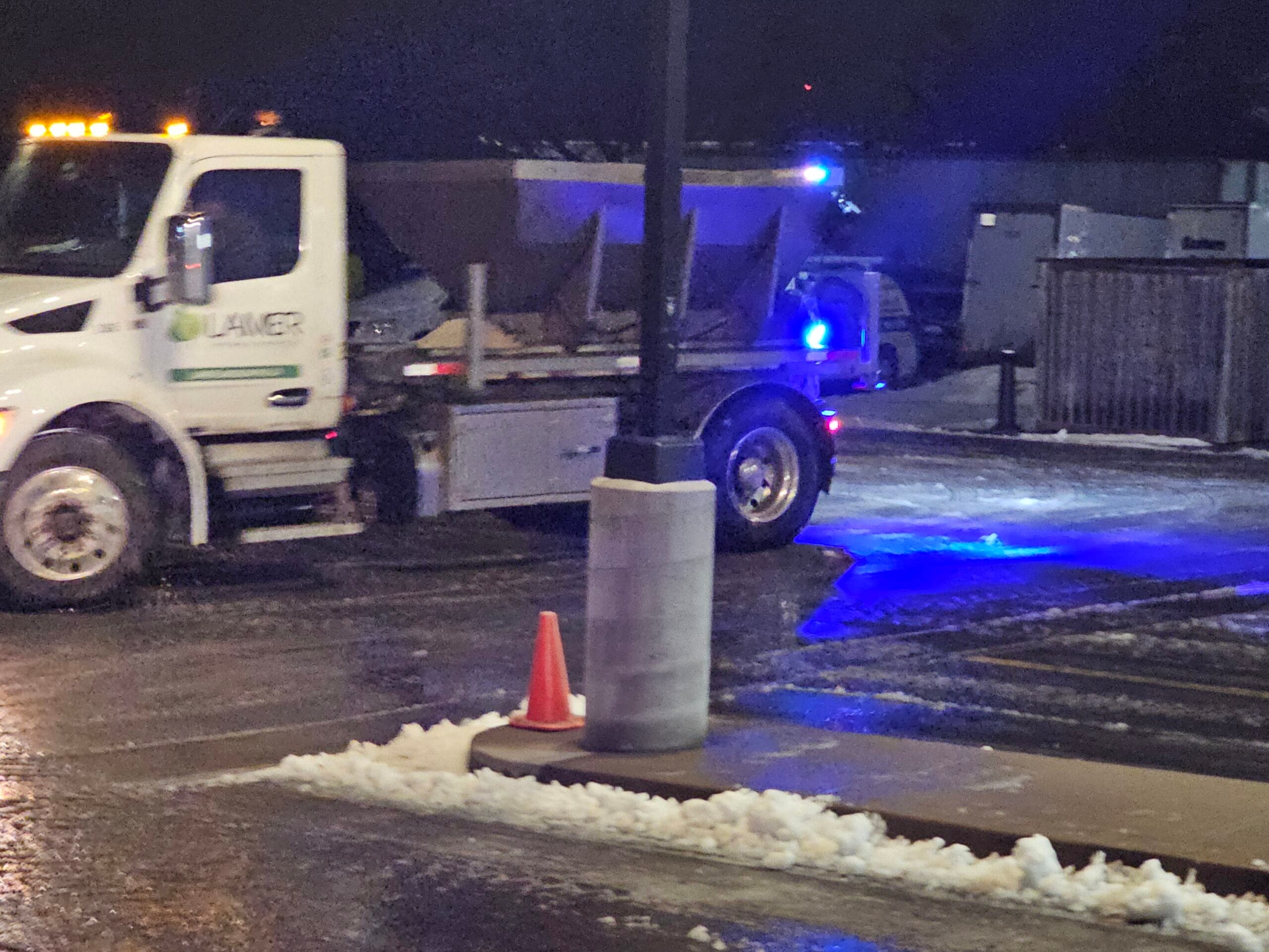 Lamer salt truck on a commercial lot before dawn during a winter storm