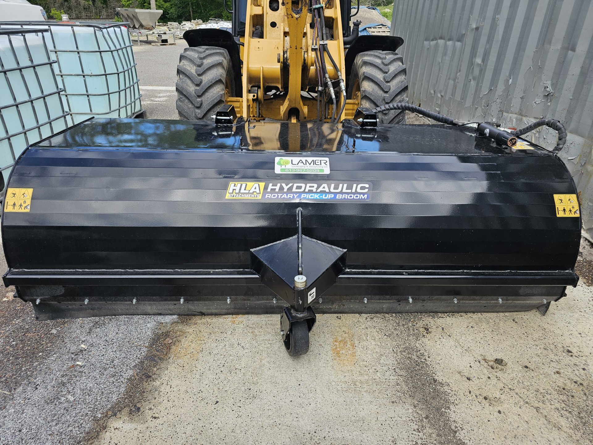 Lamer loader fitted with an HLA hydraulic rotary pick-up broom for parking lot sweeping